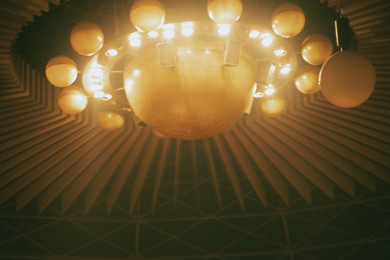 A large gold chandelier lit beneath the domed ceiling of an auditorium