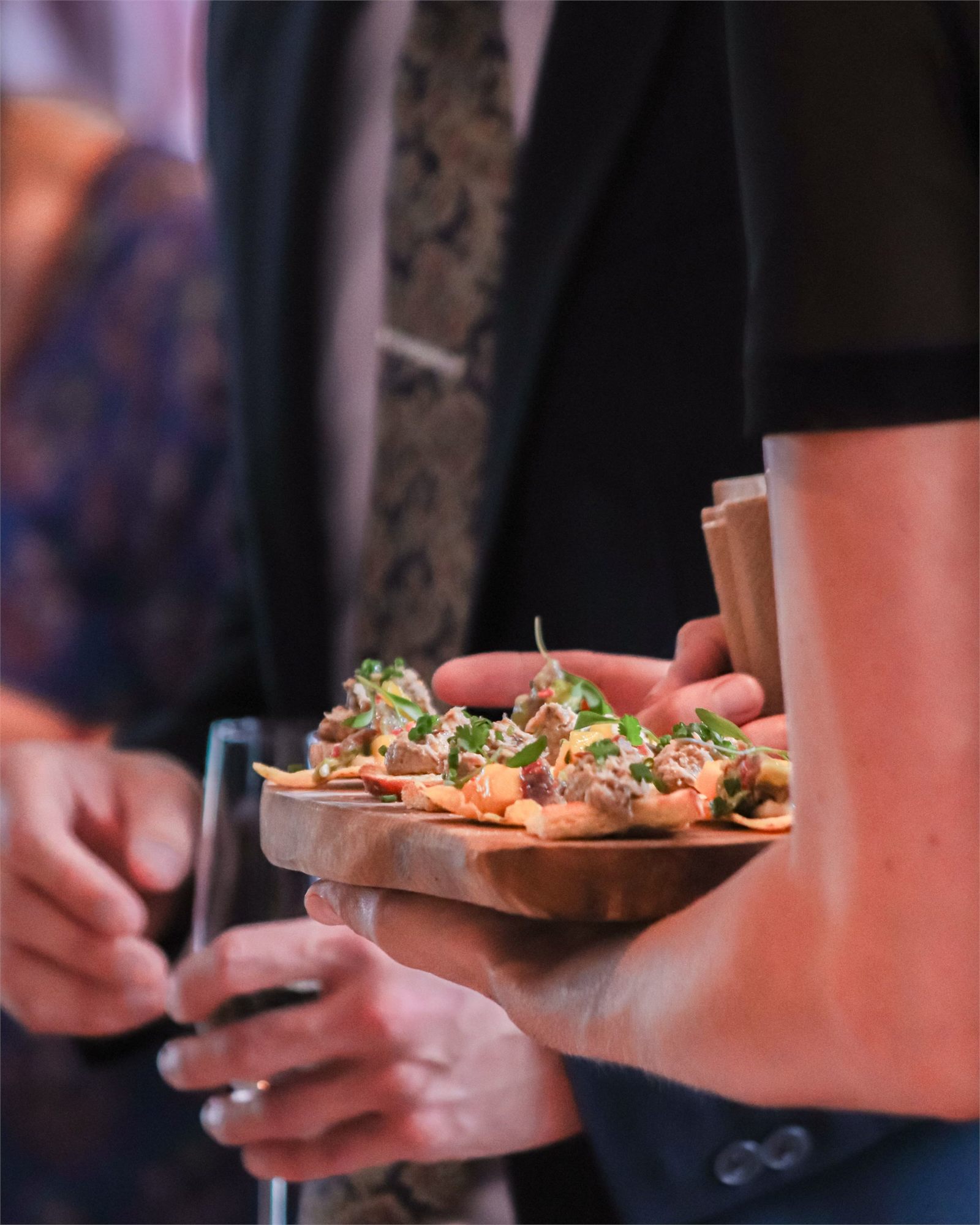 A tray of canapés carried between guests at close quarters during a drinks reception