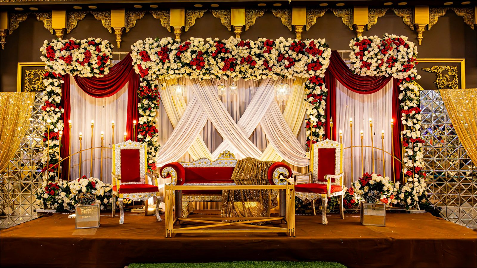 A wedding stage dressed with red and white floral arrangements