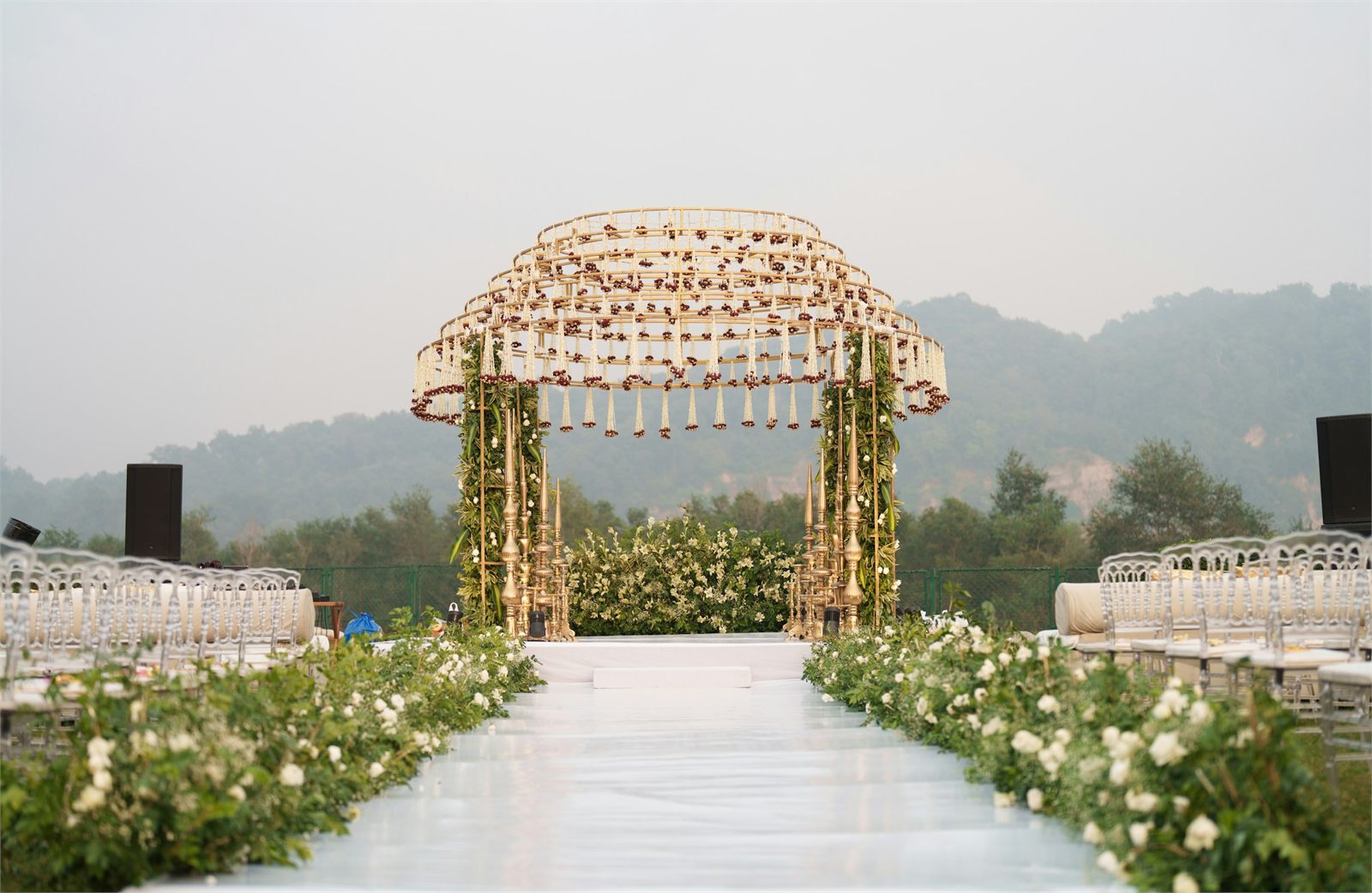 A floral arch above an aisle set with seating for a ceremony
